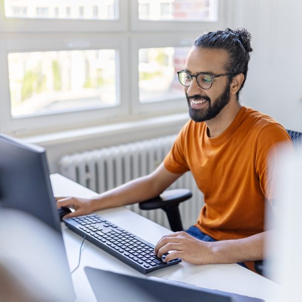 Eine Person sitzt in einem Büro vor zwei Monitoren.