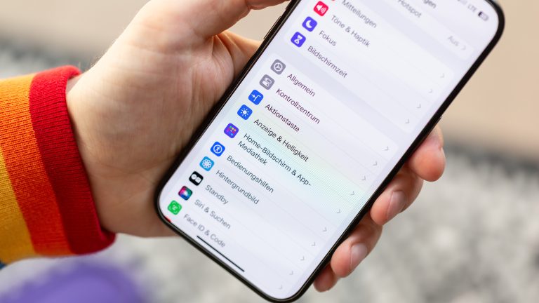 Eine Person hält ein iPhone 15 Pro in der Hand. Darauf zu sehen sind die Einstellungen. Eine Person hält ein iPhone 15 Pro in der Hand. Darauf zu sehen sind die Einstellungen.