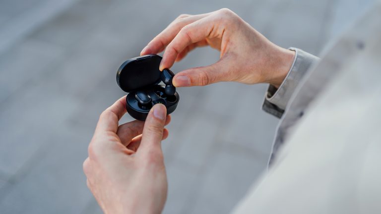 Eine Person legt einen In-Ear-Kopfhörer in sein Ladecase.