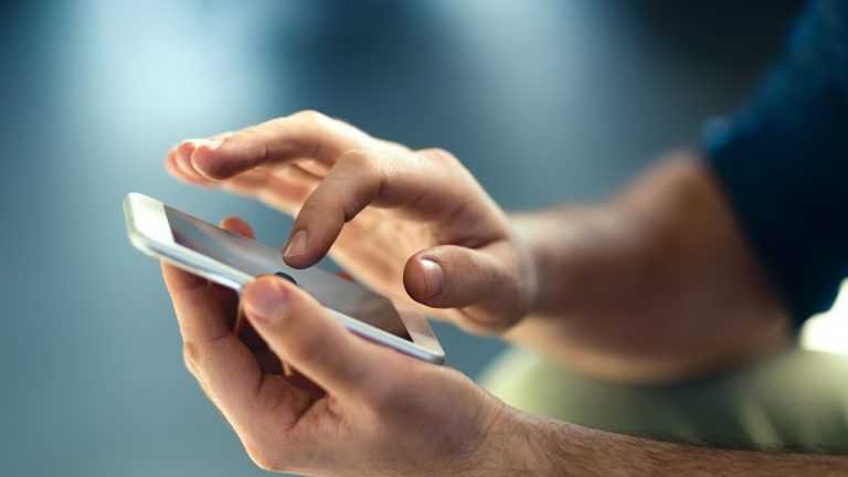 Eine Person hält ihr Smartphone vor sich und tippt mit einem Finger auf den Bildschirm. Eine Person hält ihr Smartphone vor sich und tippt mit einem Finger auf den Bildschirm.
