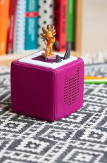 Eine pinke Toniebox steht auf einem Teppich auf dem Boden.