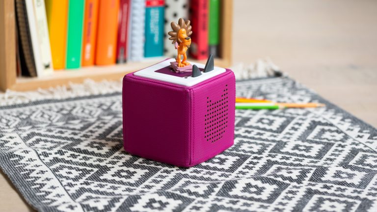 Eine pinke Toniebox steht auf einem Teppich auf dem Boden.