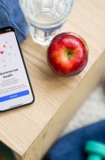 Auf einem Holztisch liegt ein iPhone. Darauf ist die Health App geöffnet.