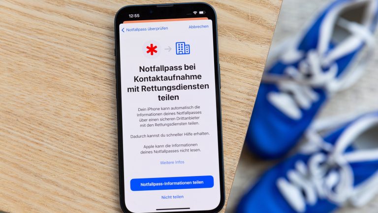 Apple Health richtig nutzen: Gesund leben mit der App Auf einem Holztisch liegt ein iPhone. Darauf ist die Option zu sehen, den Notfallpass automatisch mit Rettungsdiensten zu teilen.