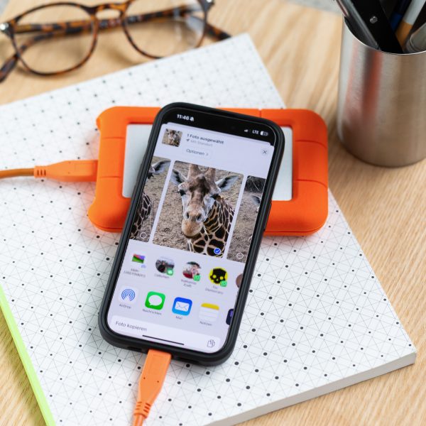 Ein iPhone 15 Pro liegt auf einem Tisch. Daran angeschlossen ist eine externe Festplatte.