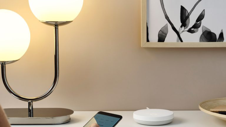 Eine Person hält ein Smartphone in Richtung eines IKEA-Gateways.