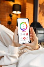 Eine Person hält ein Smartphone in der Hand, auf der die App-Steuerung von smarter Beleuchtung zu sehen ist.