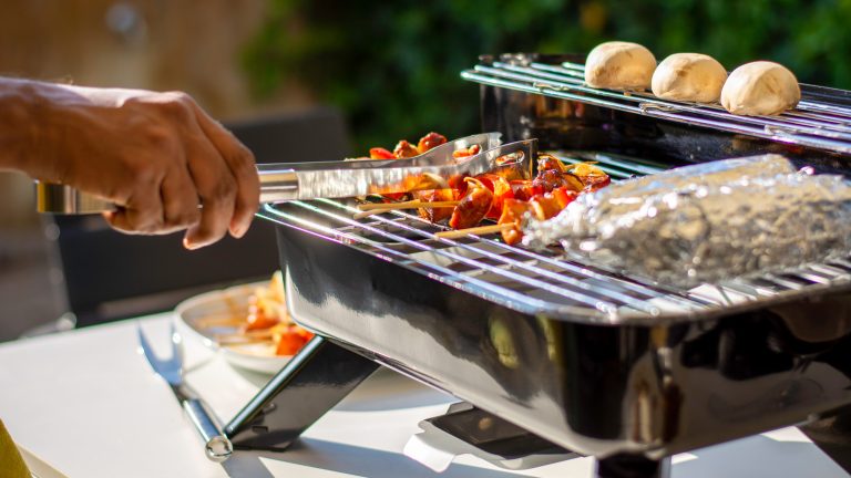 Grill und Grillrost sauber machen: Die besten Tipps und Hausmittel Eine Person wendet gerade Gemüse, das auf einem Grill liegt.