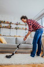 Eine Person saugt in ihrem Wohnzimmer den Teppich.