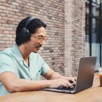 Eine Person sitzt an einem MacBook Pro und trägt dabei Sonos Ace in Schwarz.