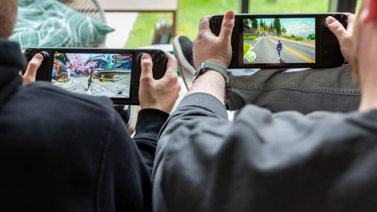 Zwei Personen sitzen nebeneinander und spielen auf einem Steam Deck OLED und Steam Deck LCD.