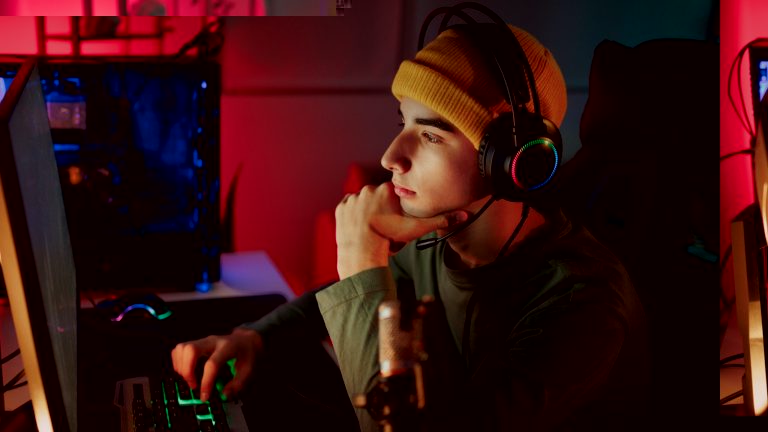 Eine Person mit Headset auf dem Kopf sitzt vor einem Gaming-Rechner.