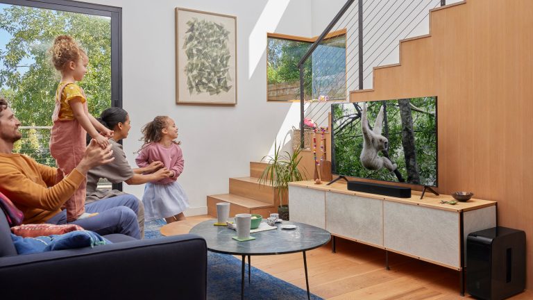 Soundbar anschliessen, Soundbar richtig einstellen, Sonos beam gen2 Eine Familie mit zwei Erwachsenen und zwei Kindern sieht im Wohnzimmer fern und hört den Ton über eine Soundbar, die direkt unter dem TV steht.