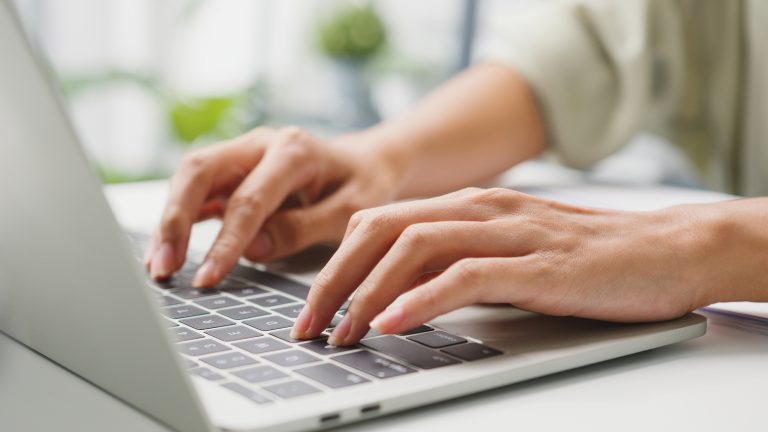 Safari-Erweiterungen, Praktische Tools für deinen Apple-Browser Eine Person sitzt vor einem MacBook und tippt auf der Tastatur.