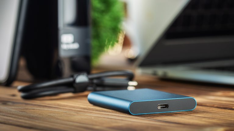 Windows 10 und 11, Festplatte klonen Schritt für Schritt Eine externe Festplatte liegt mitsamt Kabel neben einem Laptop.