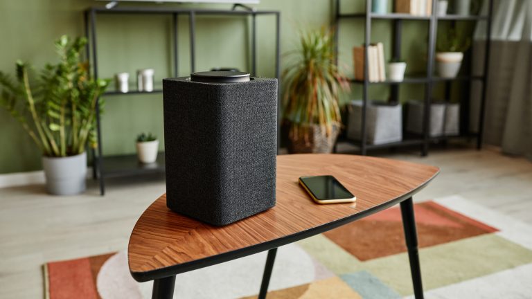 Spotify Connect Auf einem Couchtisch in einem Wohnzimmer steht ein Lautsprecher, neben dem ein Smartphone liegt.