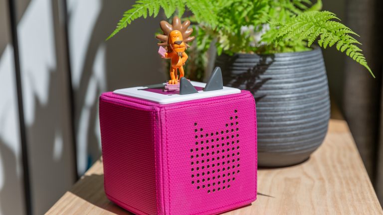 Toniebox, So kannst du den Akku wechseln Ein Löwen-Tonie steht auf einer magentafarbenen Toniebox.