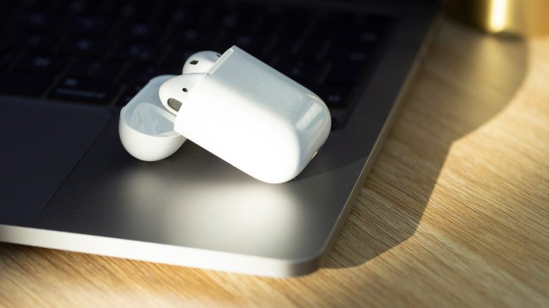 AirPods laden nicht, Das kannst du tun, wenn der Akku Probleme macht Zwei AirPods liegen in einem Ladecase auf einem Laptop.