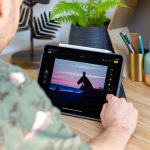 Eine Person sitzt vor einem iPad Air M2 mit angeheftetem Apple Pencil Pro und bearbeitet ein Foto über die Fotos-App.