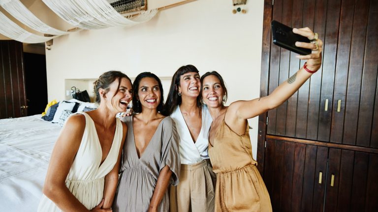 Vier Personen, eine davon scheint in einem Brautkleid zu sein, machen ein Selfie von sich.