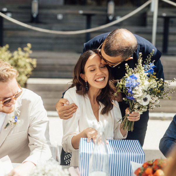 Ein Hochzeitspärchen sitzt an einem Tisch und nimmt ein Geschenk in Empfang.