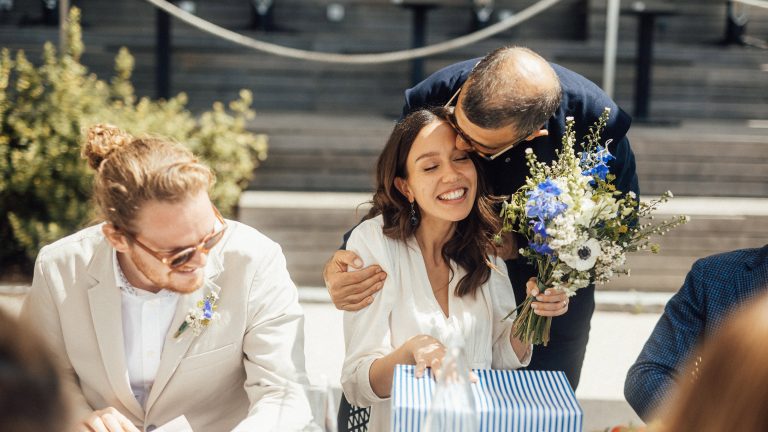 Ein Hochzeitspärchen sitzt an einem Tisch und nimmt ein Geschenk in Empfang.