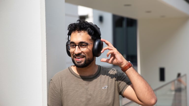 Sonos Ace und Apple AirPods Max, Modische Kopfhörer im Vergleich Eine Person steht draußen im Sonnenschein und trägt die Sonos Ace auf dem Kopf.