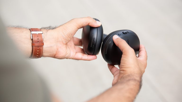Sonos Ace und Apple AirPods Max, Modische Kopfhörer im Vergleich Eine Person hält die Sonos Ace in der Hand, die Knöpfe sind deutlich sichtbar.