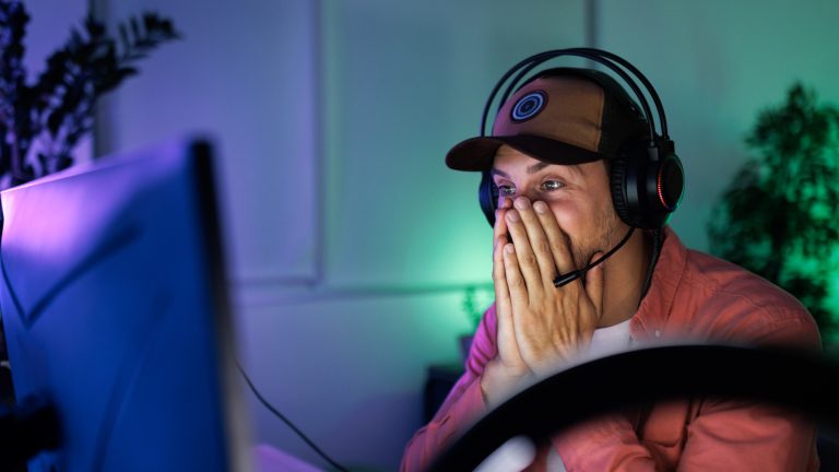 Soundboards bei Discord verwenden, Der ultimative Ratgeber Eine Person mit Headset auf dem Kopf hält sich die Hände vor das Gesicht.