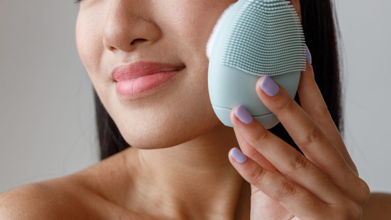 Gesichtsreinigung, Technologien für deine Skin Care Eine Person hält eine runde Schallbürste aus Silikon an ihre Wange.