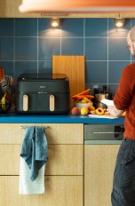 Eine Person schneidet in eine rKüche Früchte, neben ihr ist ein Airfryer von Philips zu sehen.)