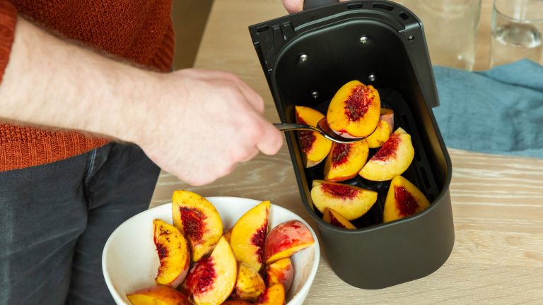 Philips 3000 Series Dual Basket Airfryer, Doppelt gut Eine Person nimmt mit einem Löffel Früchte aus dem Korb eines Airfryers.
