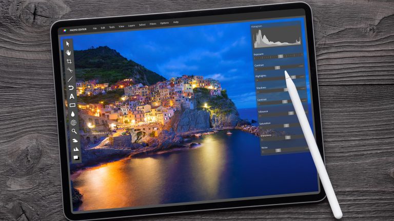 RAW-Bilder bearbeiten, Tipps und Programme Ein iPad mitsamt Pencil liegt auf einer Holzoberfläche. Auf dem Display ist eine Blidbearbeitungsprogramm zu sehen.