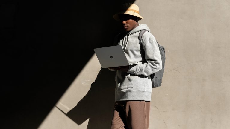 Semesterstart, Gut gerüstet mit Laptop, Tablet und Co Eine Person lehnt an einer Wand und schaut in einen aufgeklappten Laptop.