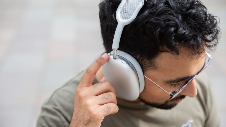 Sonos Ace und Apple AirPods Max, Modische Kopfhörer im Vergleich Eine Person trägt die AirPods Max auf dem Kopf und bedient die Digital Crown.