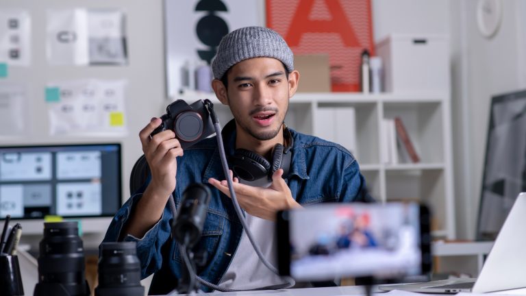 Videos schneiden, Tipps und Anleitungen für dein Video Eine Person hält eine Kamera in der Hand und filmt sich mit einem Smartphone.