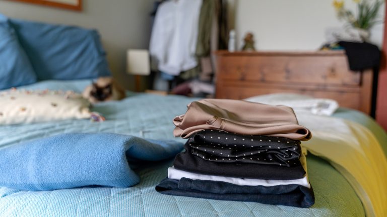 Wärmepumpentrockner - das können sie Ein Stapel Feinwäsche liegt auf einem gemachten Bett.