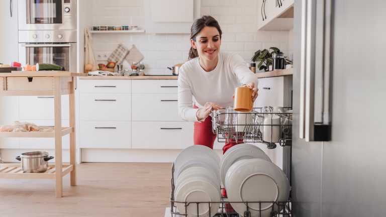 Günstige Spülmaschinen, Modelle unter 400 Euro Eine Person räumt eine Tasse in eine Spülmaschine.