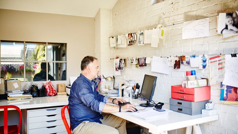 Windows 10 und 11 Taskleiste anpassen, Ausblenden, verschieben und mehr Eine Person sitzt in ihrem Arbeitszimmer an einem Schreibtisch vor einem Bildschirm.