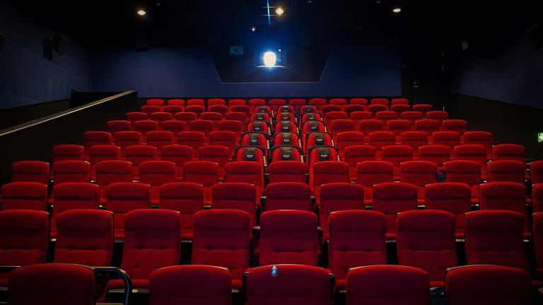 Full-HD, 4K und Co., HD-Auflösungen im Überblick Blick in einen menschenleeren Kinosaal mit roter Bestuhlung.
