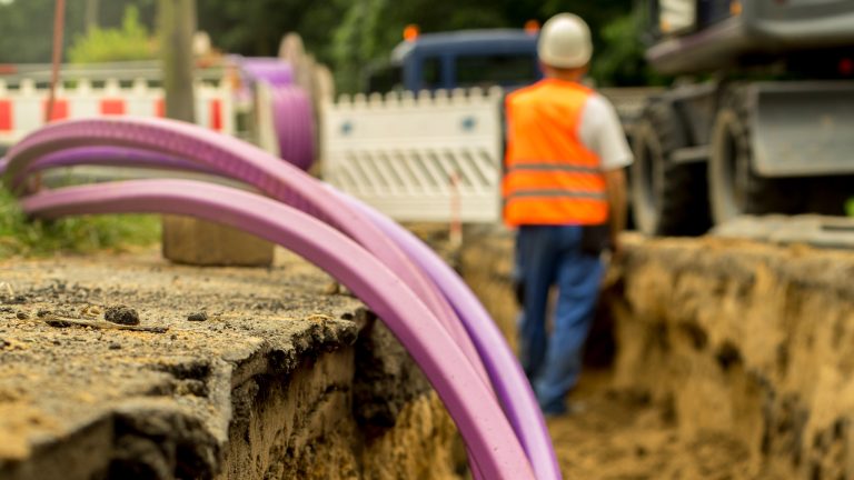 Glasfaser, Das verbirgt sich hinter dem schnellen Internet Bauarbeiter verlegen Glasfaserkabel auf einer Baustelle unter der Erde.