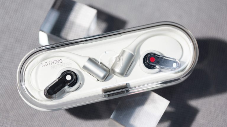 Nothing Ear (open), Stilvolles Design und innovative Technologie Zwei Nothing Ear (open) Buds liegen in dem zugehörigen Ladecase auf zwei durchsichtigen Würfeln auf einem Stoffuntergrund.