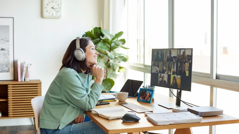 Mini-PC, Was ist das und eignet er sich auch fürs Gaming? Eine Person sitzt an einem Schreibtisch. Auf dem Monitor vor ihr findet eine Videokonferenz statt.