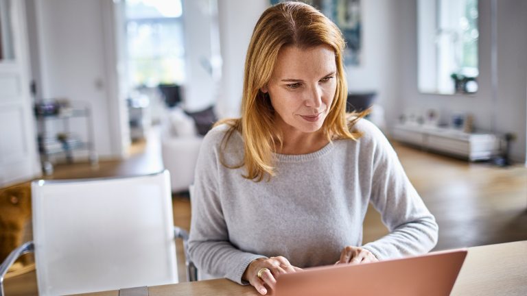 Software-Frühjahrsputz, So machst du Programme fit für 2025 Eine Person sitzt an einem Esstisch im Wohnzimmer vor einem Laptop.