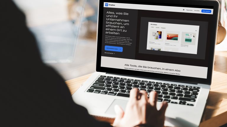 Minimalistisch leben, Mit digitalen Tools und analogen Hilfsmitteln entrümpeln-leben-1 Rückansicht einer Person, die vor einem geöffneten Notebook sitzt. Der Screen zeigt die Dropbox-На главную.
