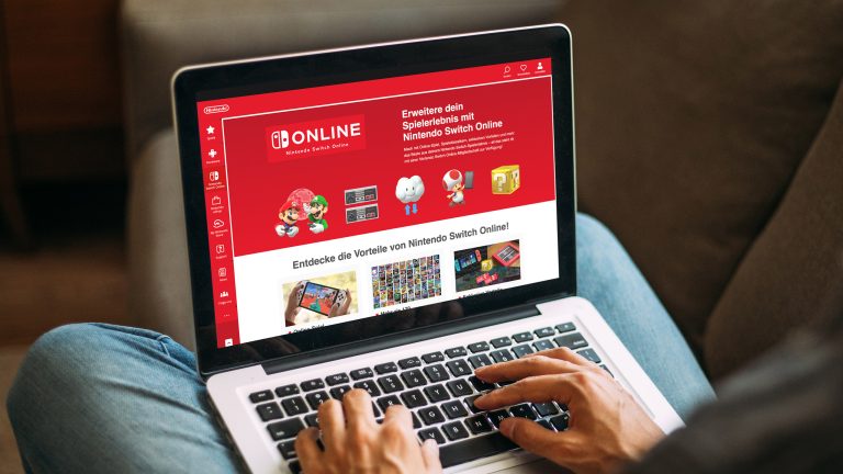 Nintendo Switch Online, Tarife, Vorteile und mehr Eine Person sitzt vor einem MacBook Pro, auf dem die Seite von Nintendo Switch Online zu sehen ist.