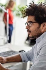 Eine Person sitzt in einem Büro vor einem Laptop und nutzt das Touchpad.