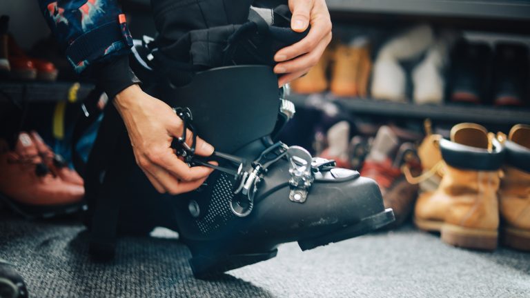 Technik meets Wintersport, Gadgets für Ski- und Snowboardfans Nahaufnahme eines Skischuhs am rechten Fuß einer Person, die diesen gerade schließt.
