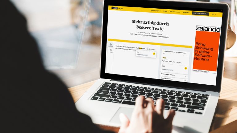 Rechtschreibprüfung, Diese Tools korrigieren Texte kostenlos Ein Notebook steht auf einer hölzernen Schreibtischplatte. Im Browser ist der Duden-Mentor geöffnet.