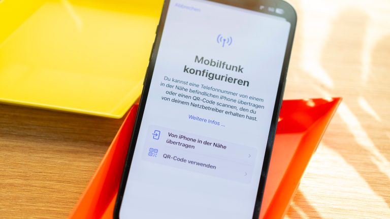 eSIM vs. Klassische SIM, Unterschiede, Vor- und Nachteile Auf einem iPhone ist die Funktion zu Mobilfunk-Konfiguration geöffnet. Es liegt auf einer bunten Unterlage.